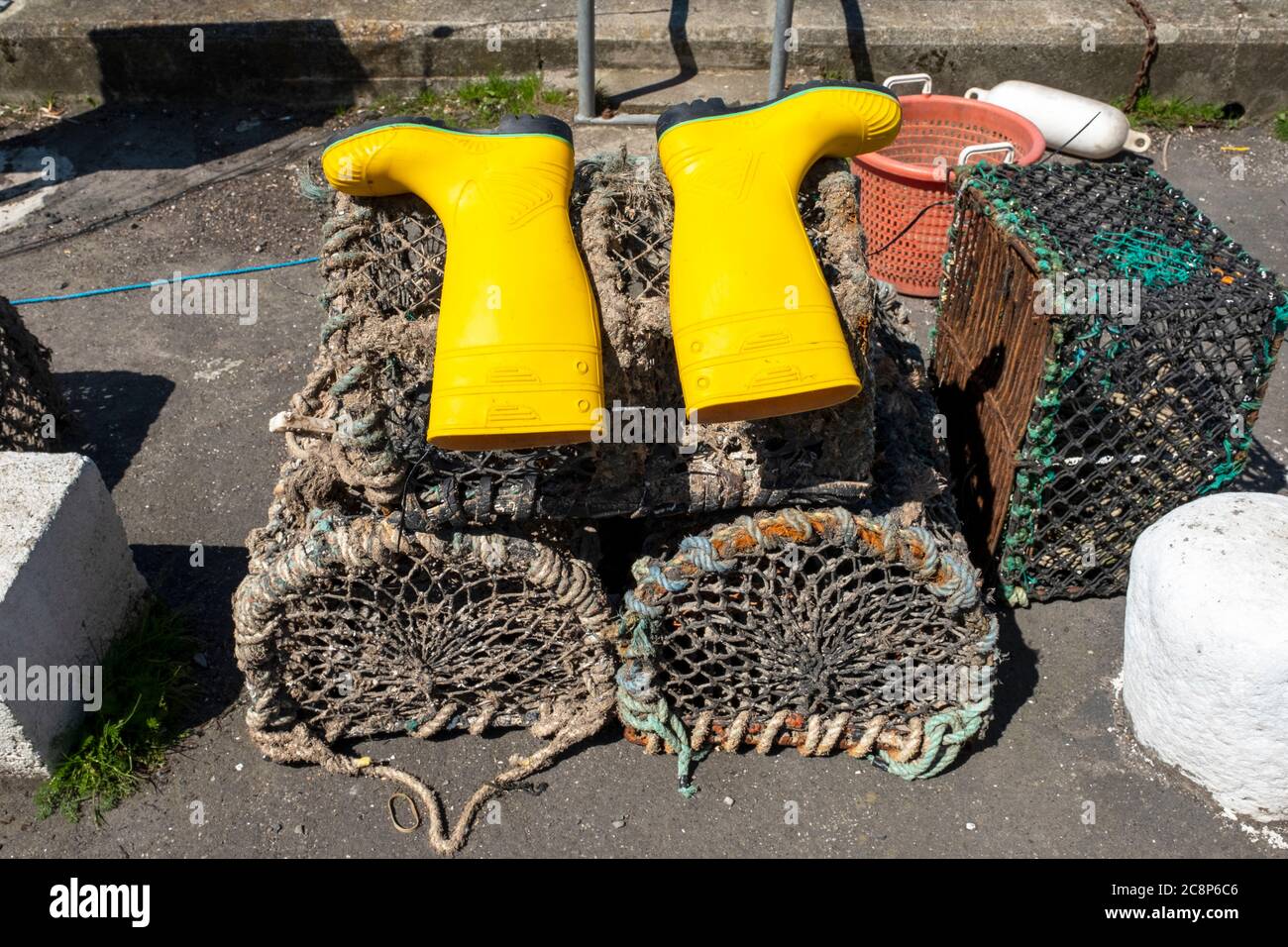 Yellow wellington boots laid out to dry on lobster creels in the harbour, Isle of Whithorn, Dumfries & Galloway, Scotland. Stock Photo