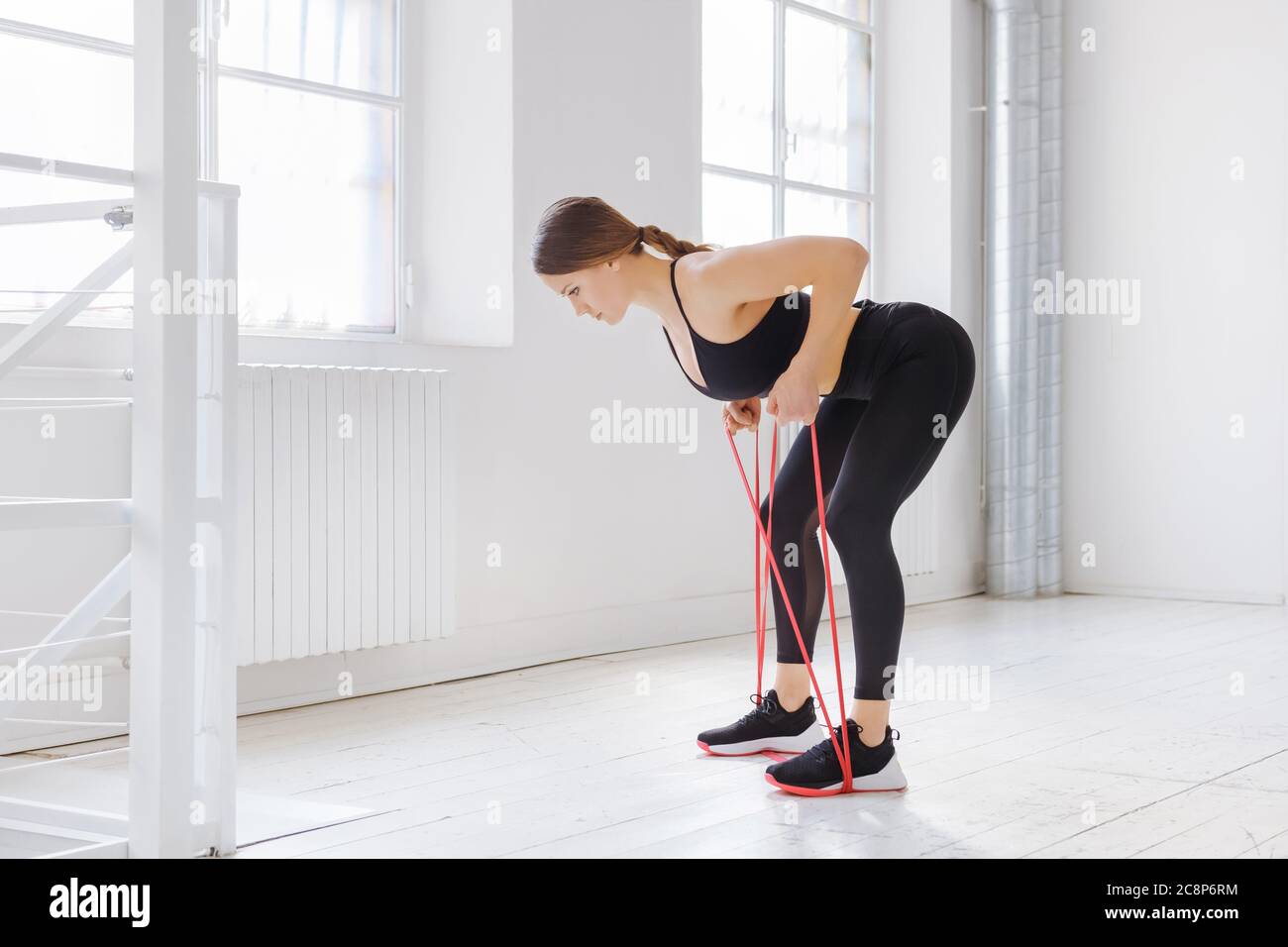 Young woman doing rower resistance exercises with a power band in a