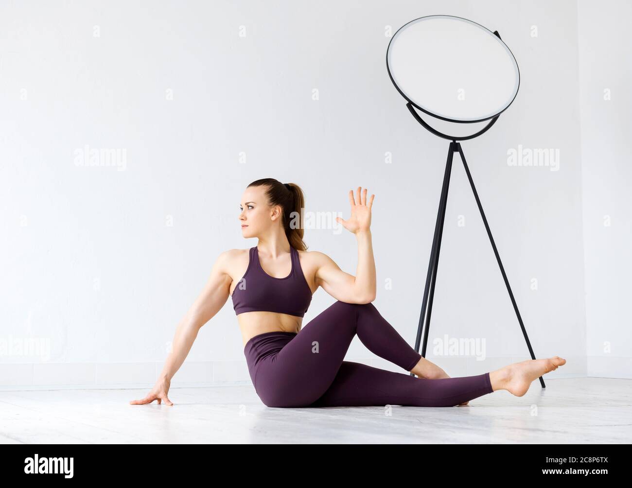 Athletic young woman doing twist stretching exercises on the floor in a  high key gym in a health and fitness concept to tone her lower back muscles  Stock Photo - Alamy
