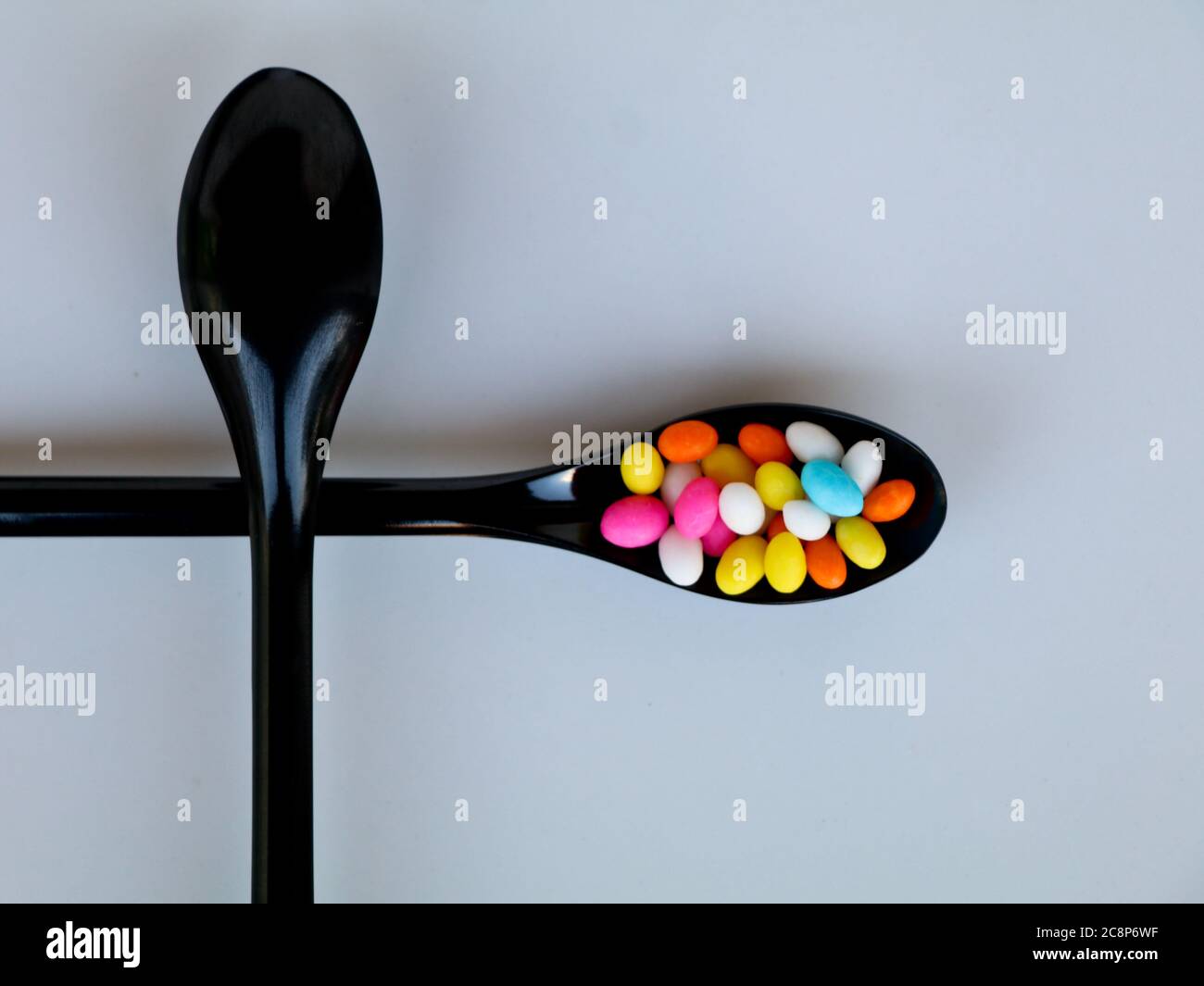 Multi colored sweet fennel sugar candy in black spoons against white