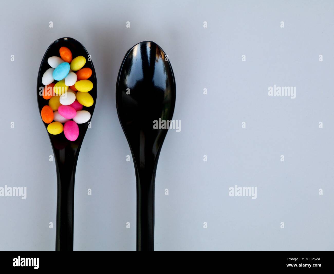 Multi colored sweet fennel sugar candy in black spoons against white