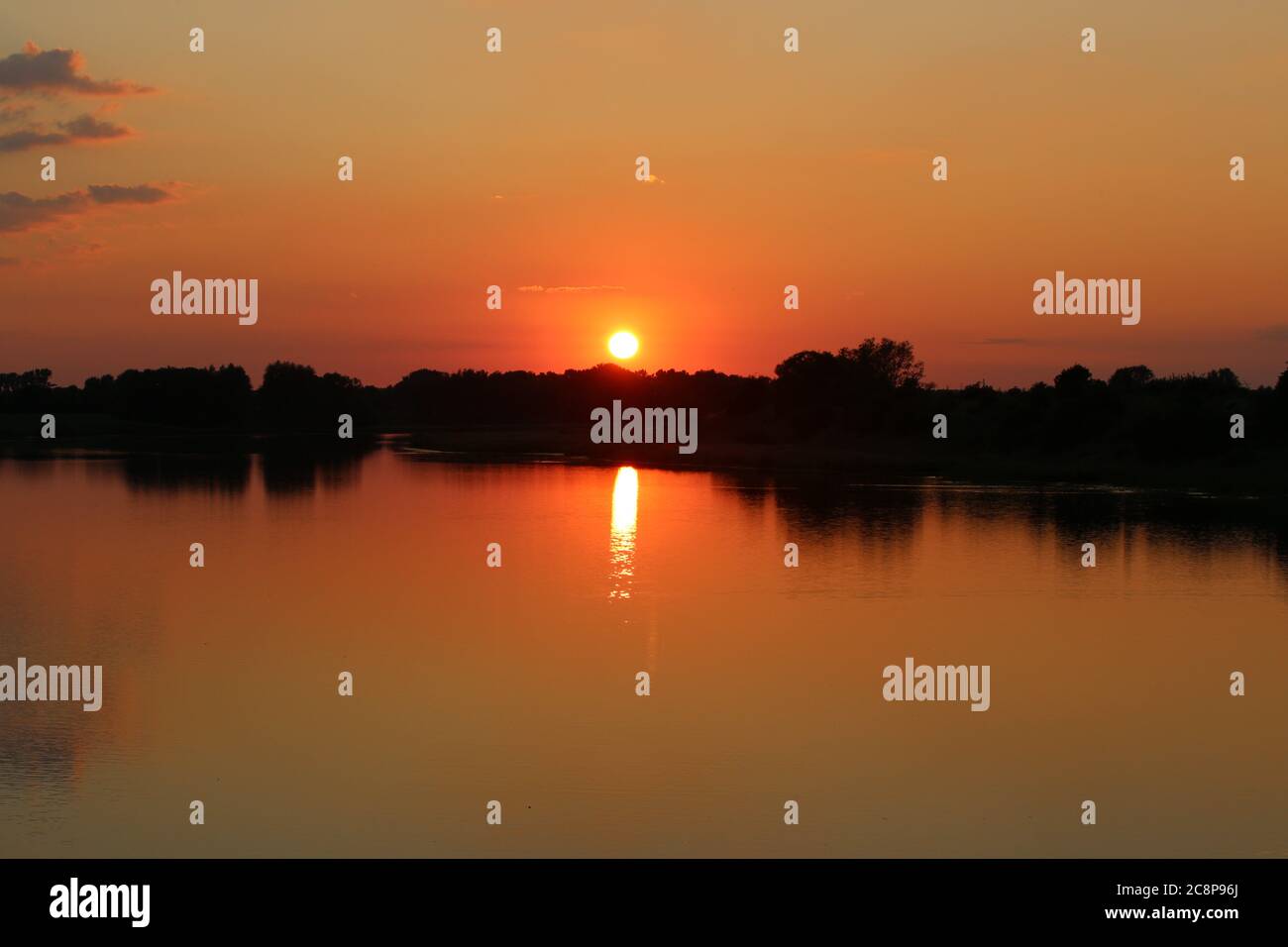 A sunset at a lake with trees on the bank of the lake Stock Photo