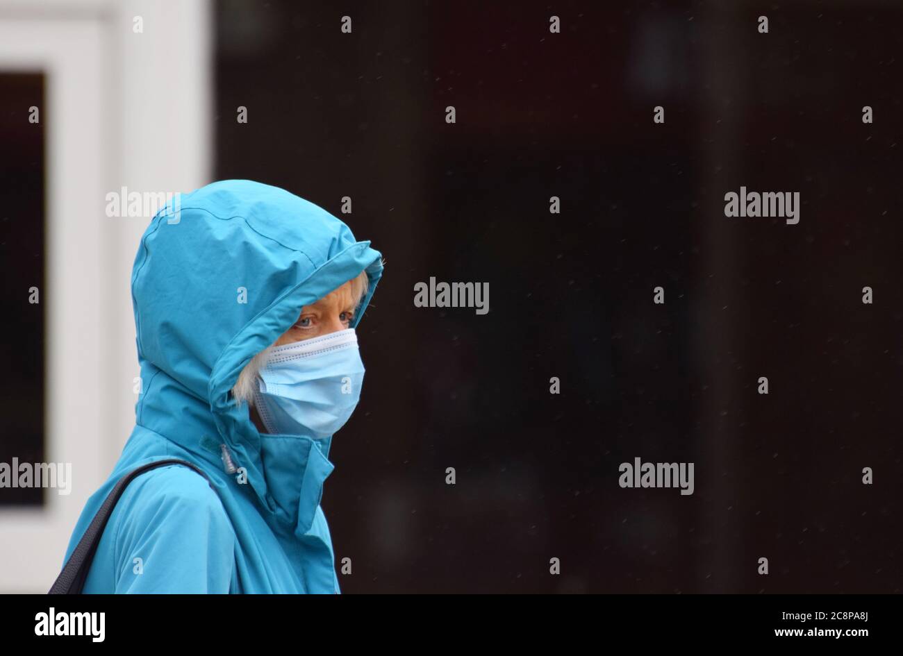 A woman aged 60 crosses the street in England following a law being passed making wearing face coverings compulsory in Retail Settings on July 24 2020 Stock Photo