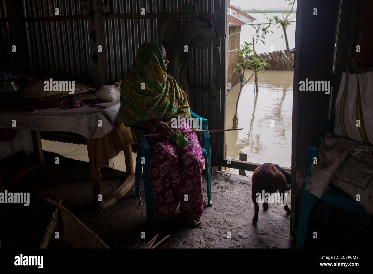 A sick woman sitting in her flood inundated house Stock Photo