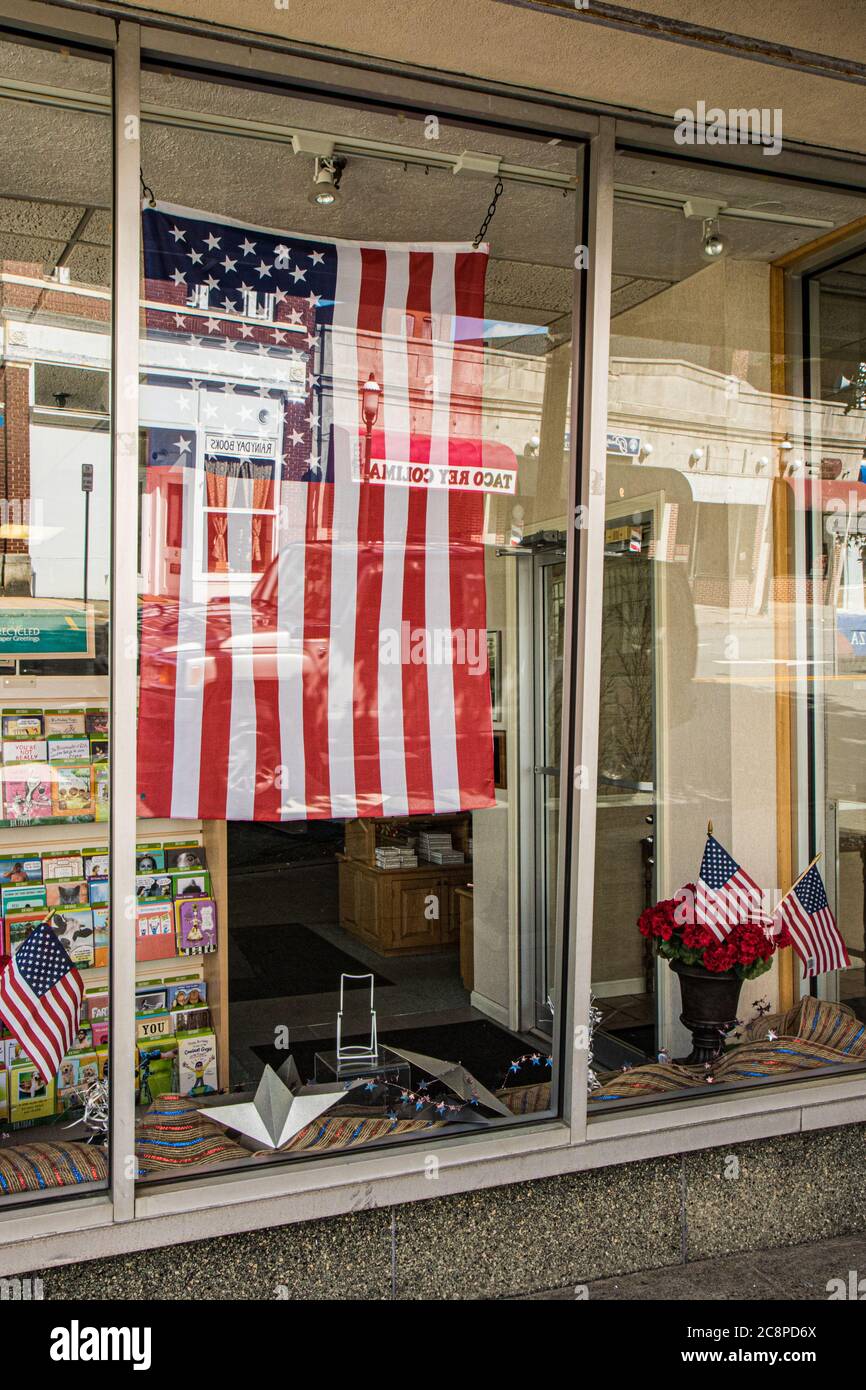 An American flag hangs in a store front window in Gardner, Massachusetts Stock Photo