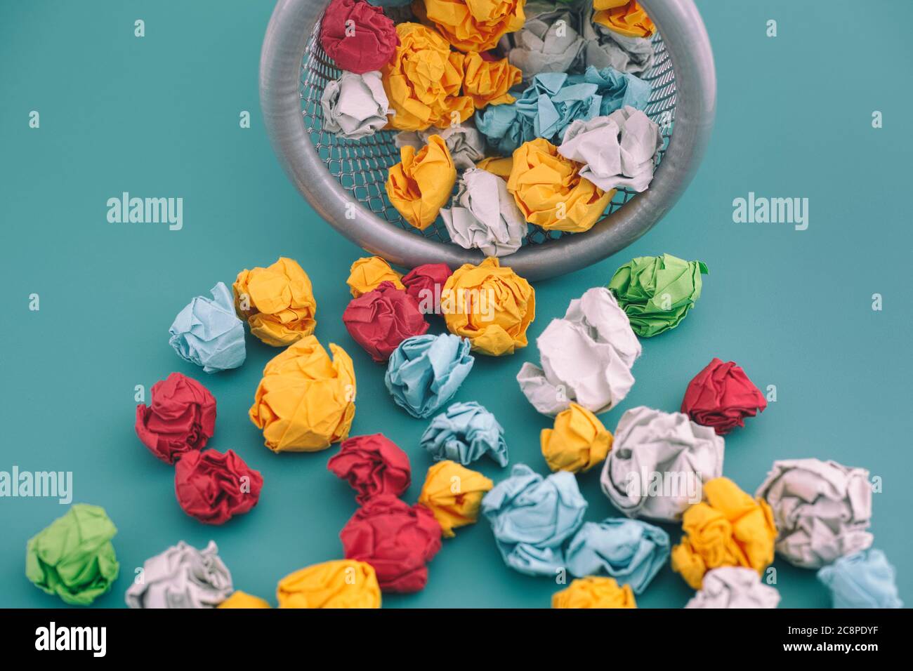 Colorful crumpled paper balls rolling out of a trash can. Idea Concept. Stock Photo