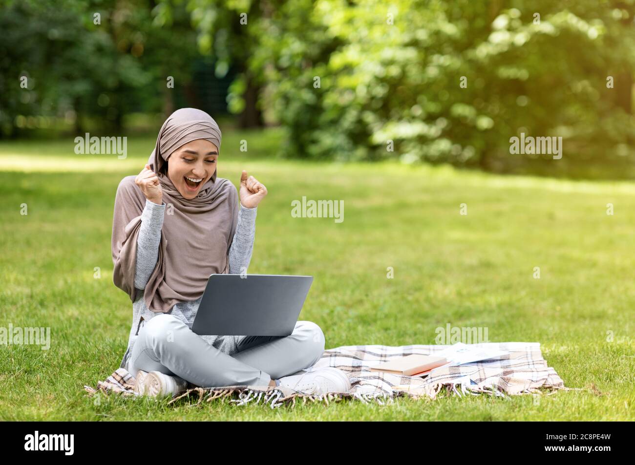 Emotional arab girl looking at laptop and screaming Stock Photo