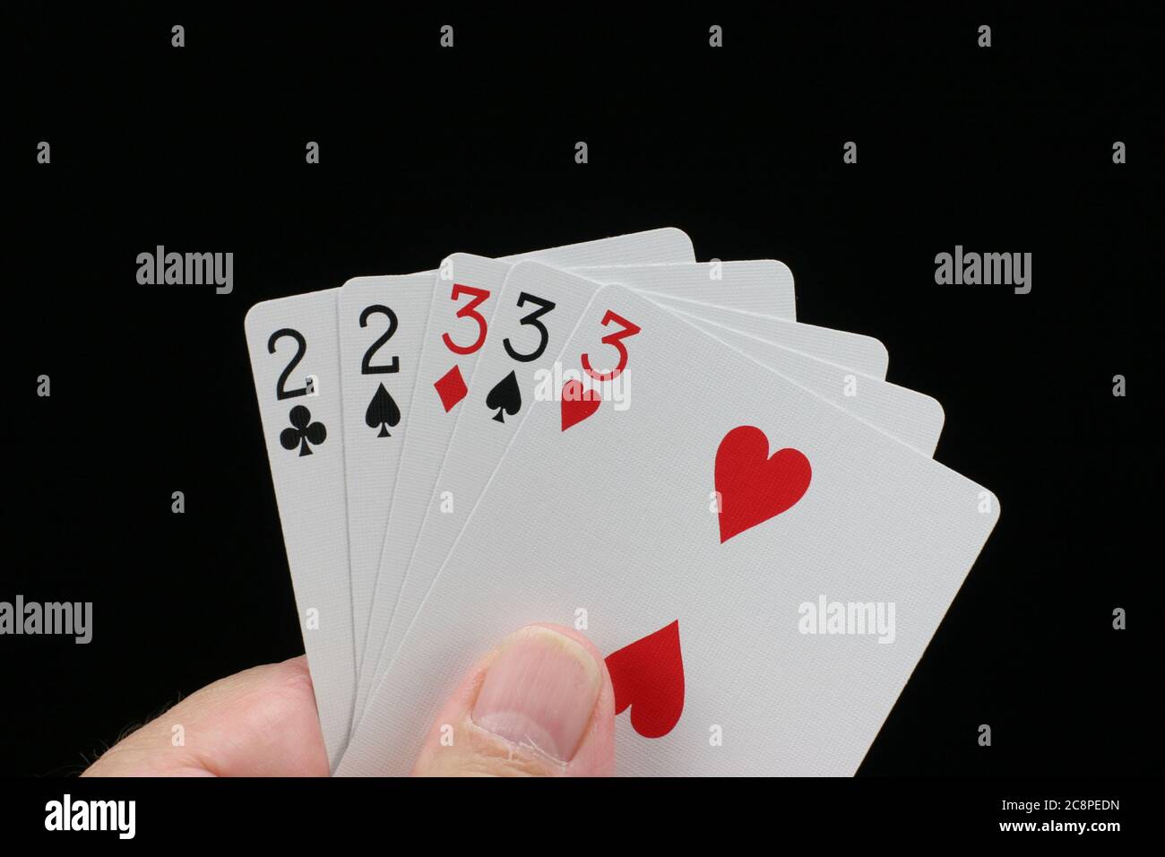 Hand holding full house poker hand on black background. Stock Photo