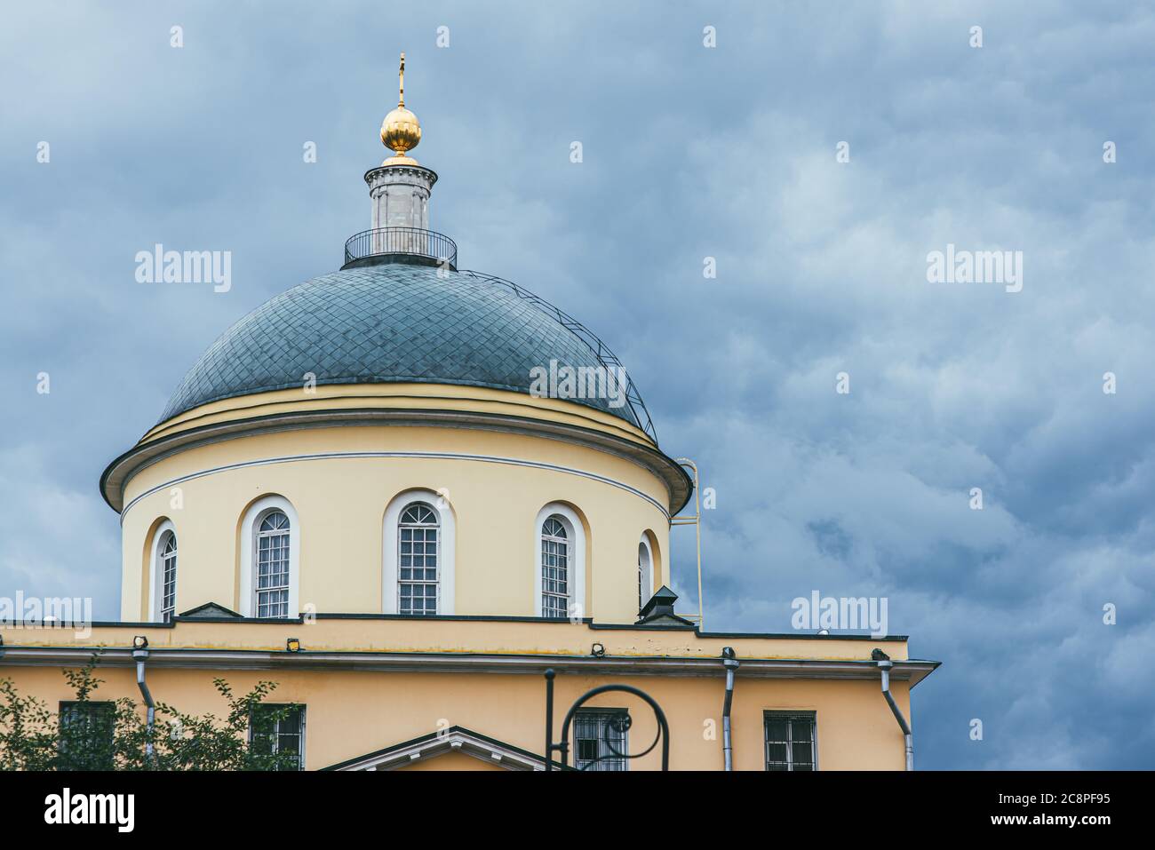 A green dome with elongated arched windows topped with a golden dome against a stormy sky. Capital of the Russian Empire Moscow Stock Photo