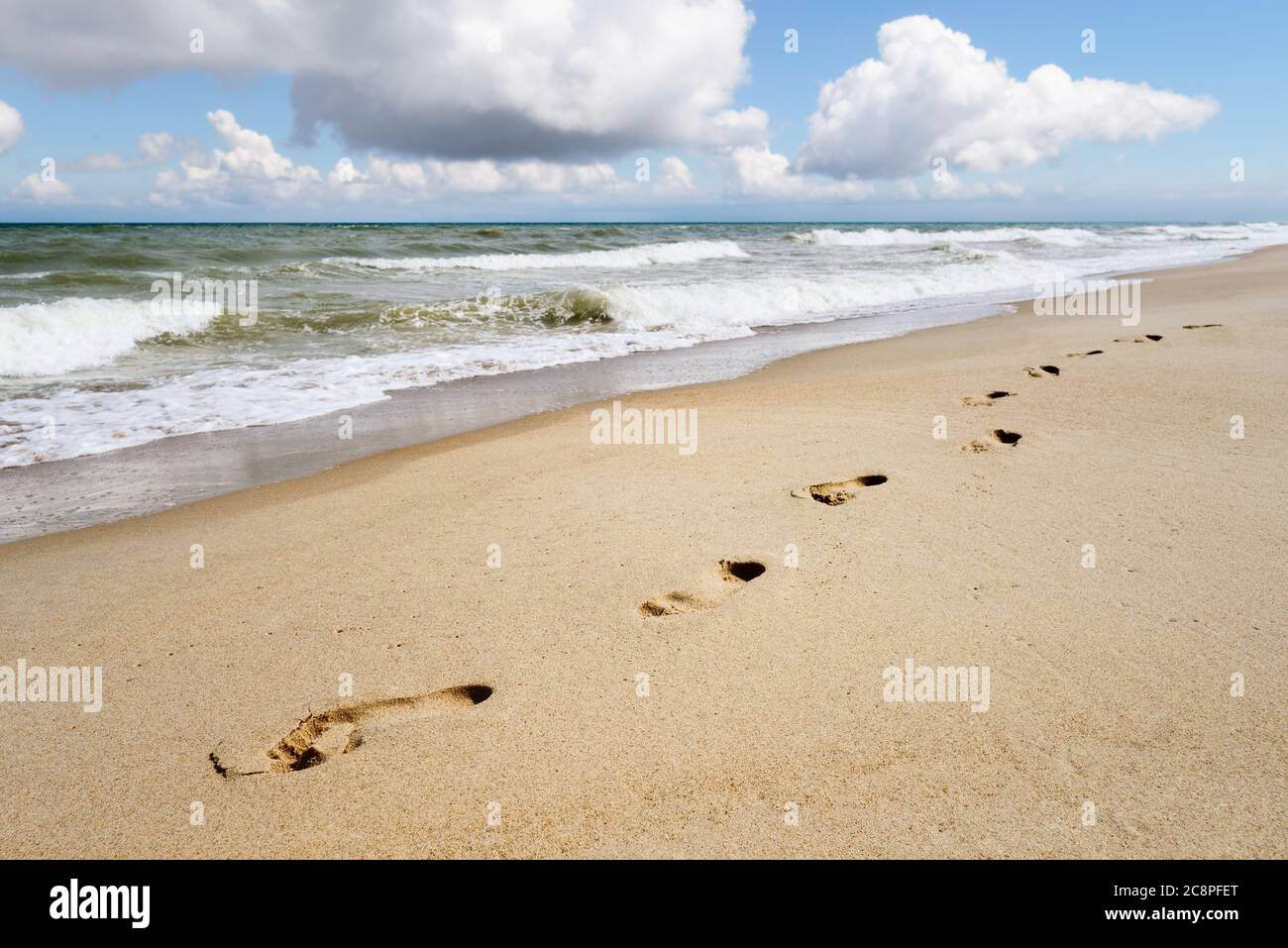 Background on the theme of a summer seaside resort. Footprints on a sandy beach by the sea. Sunny landscape Stock Photo