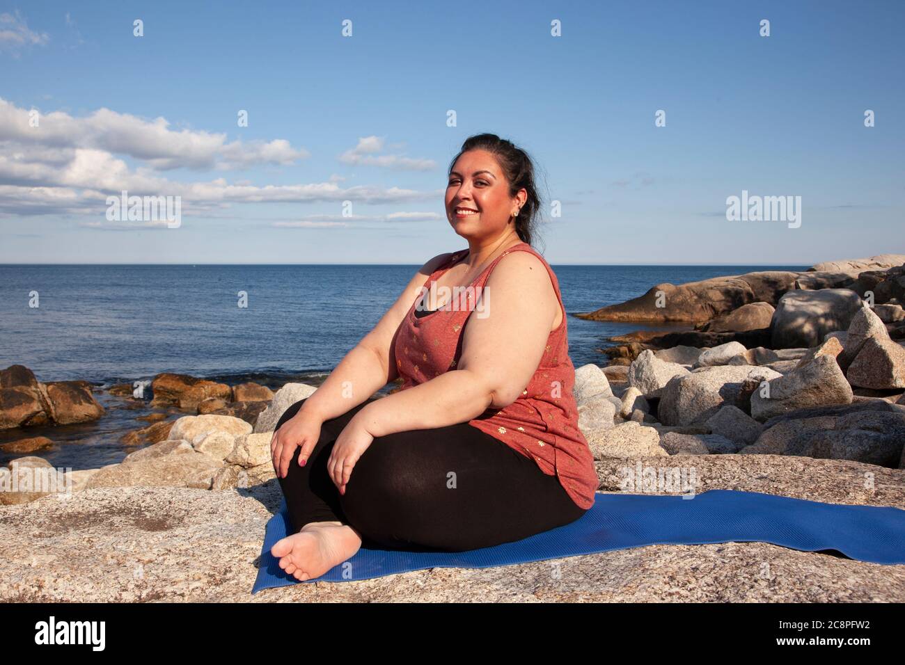 glowing sunny woman smiling at the camera for a portrait by the ocean while  doing yoga Stock Photo - Alamy