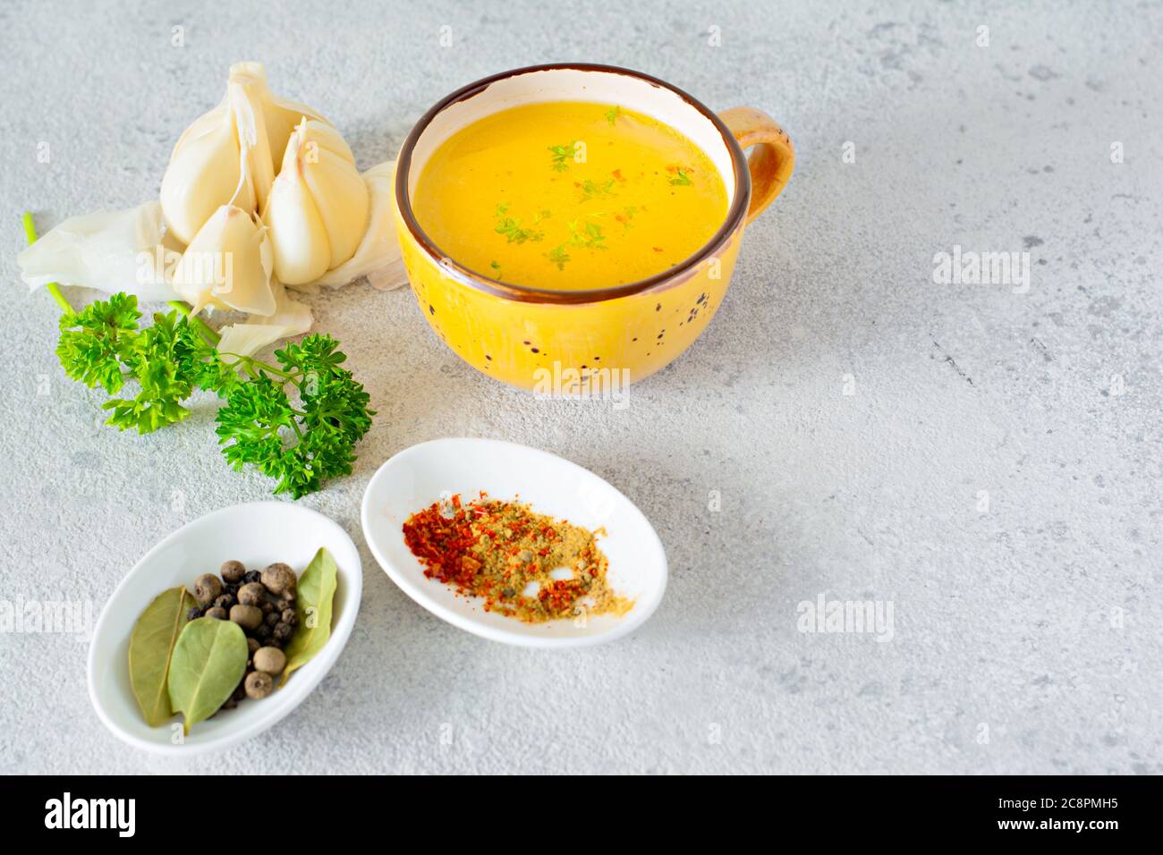 Homemade chicken (bone) broth/bouillon with vegetables, spices and herbs in a bowl (cup) on a light background. Natural collagen of animal origin. Liq Stock Photo
