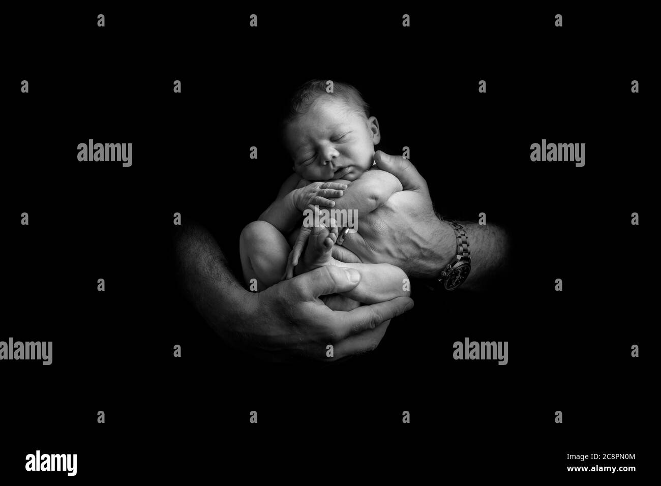 Sleeping newborn baby being held in hands of father Stock Photo