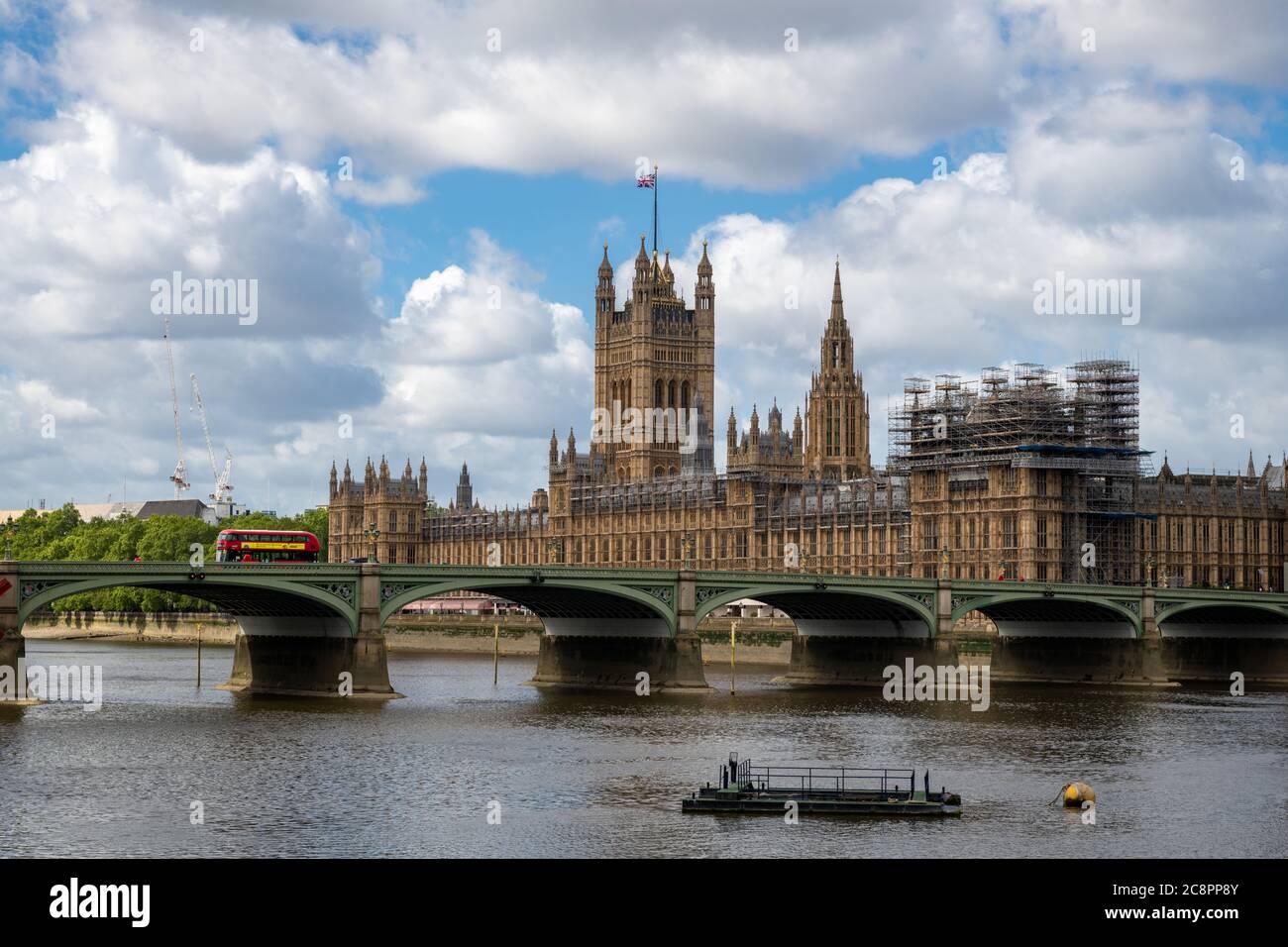 Westminster Bridge with a double decker bus crossing and the house of parliament on a beautiful day with blue sky clouds. Stock Photo