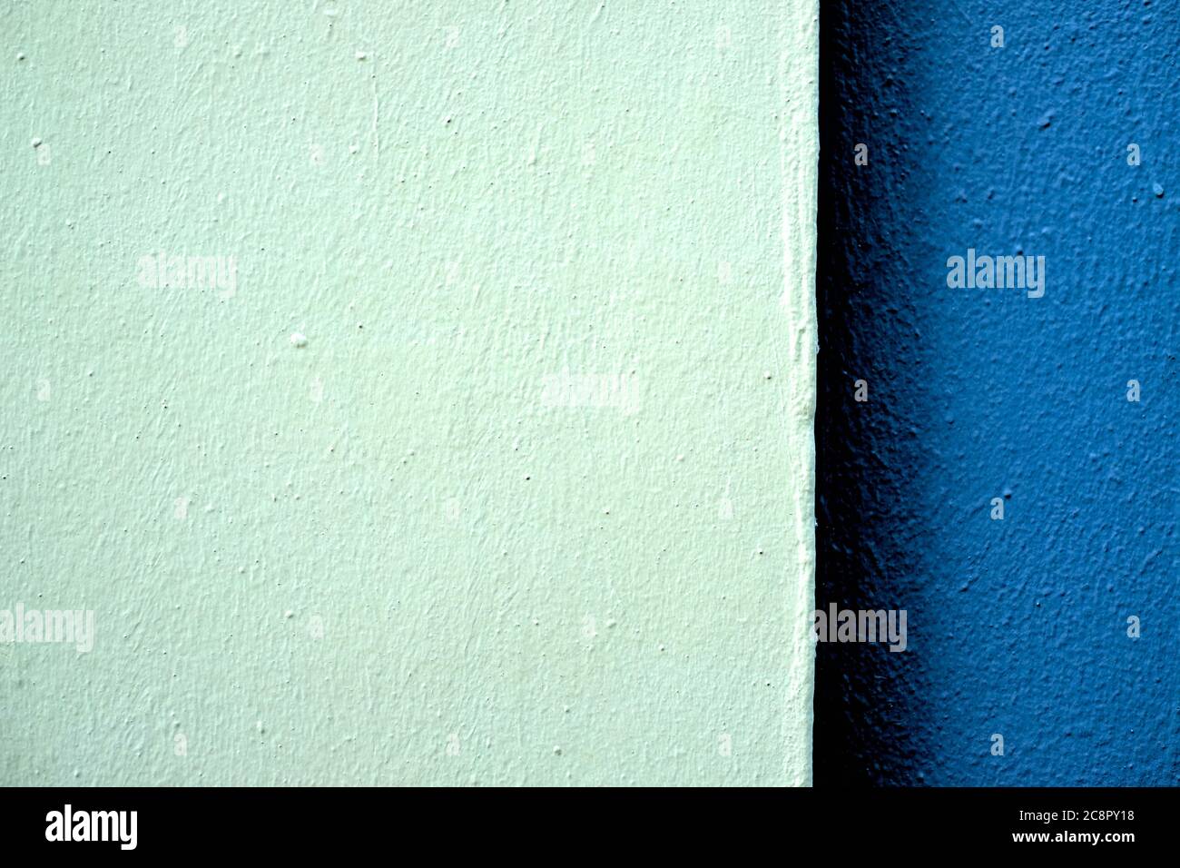 Two tones of blue color bands on a freshly painted wall in hard light, offset with large ligher part. Stock Photo