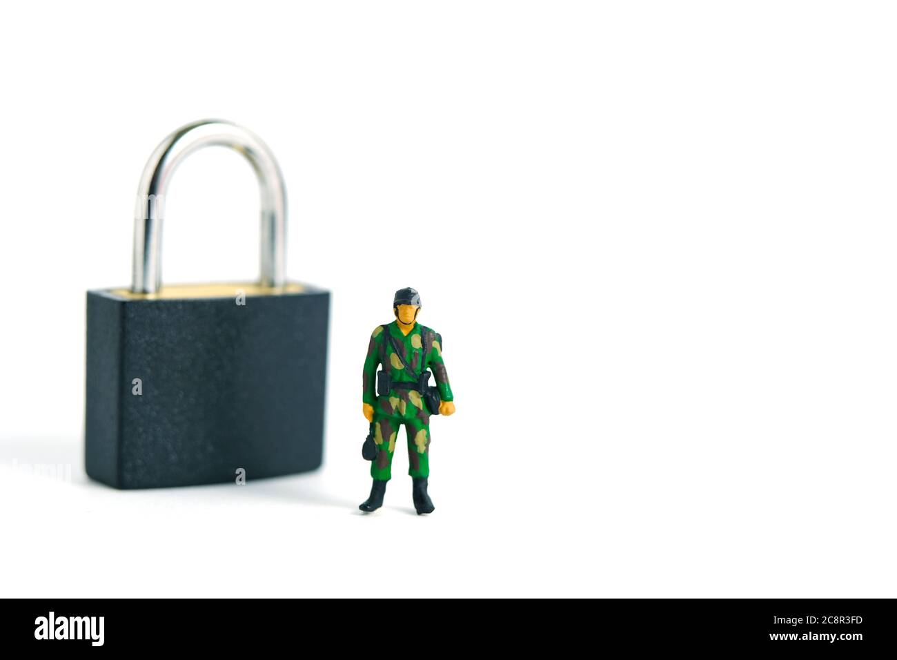 Pandemic coronavirus conceptual miniature people photography – Lockdown illustration – miniature soldier stand guard in front of padlock. Image Photo Stock Photo