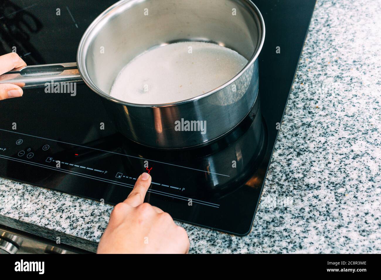 Female hand turns on electric hob closeup. Process to cook an apple