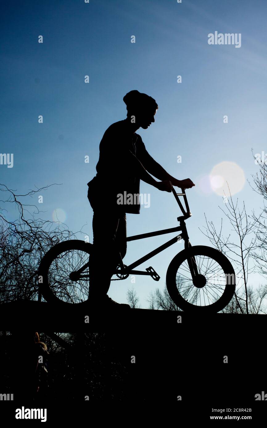 Biker is standing with a bicycle on a background of dark sky. Sport lifestyle. Stock Photo