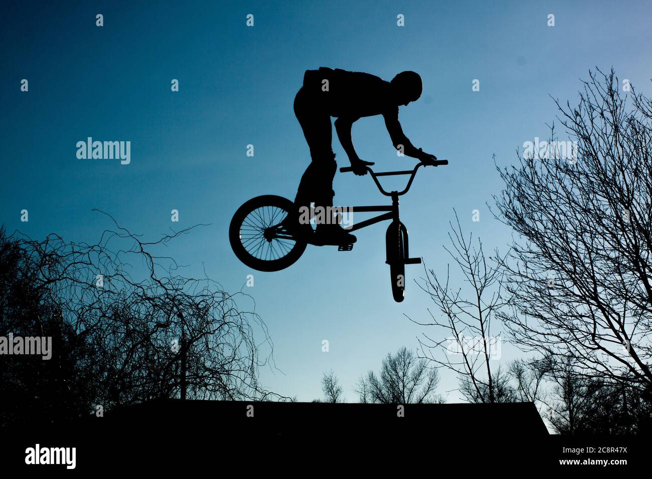 Urban athlete biker performing acrobatic jump. Guy riding bmx bicycle at extreme sport competition. Alternative lifestyle concept. Stock Photo
