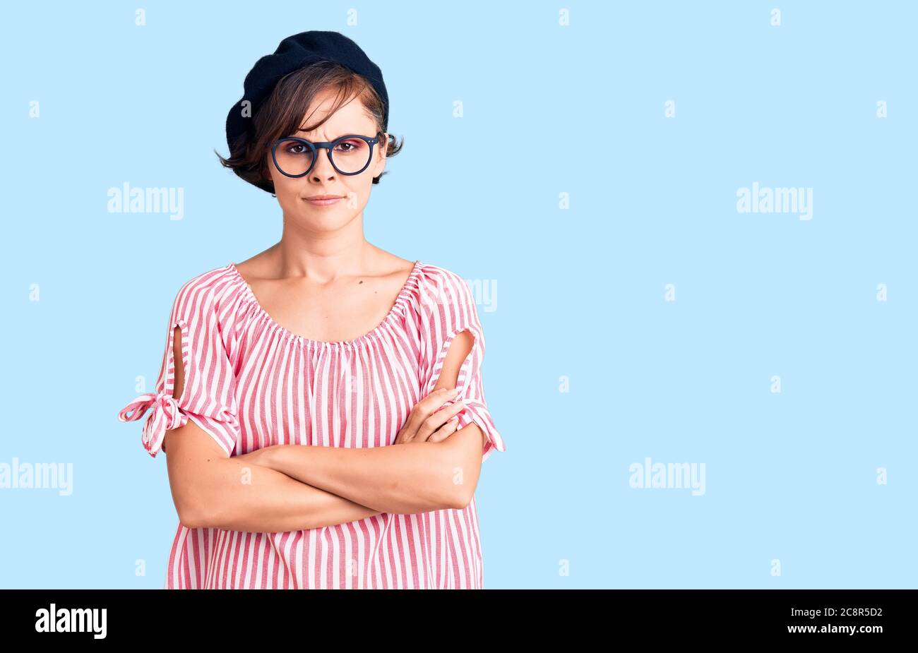 Beautiful young woman with short hair wearing casual clothes and glasses skeptic and nervous, disapproving expression on face with crossed arms. negat Stock Photo