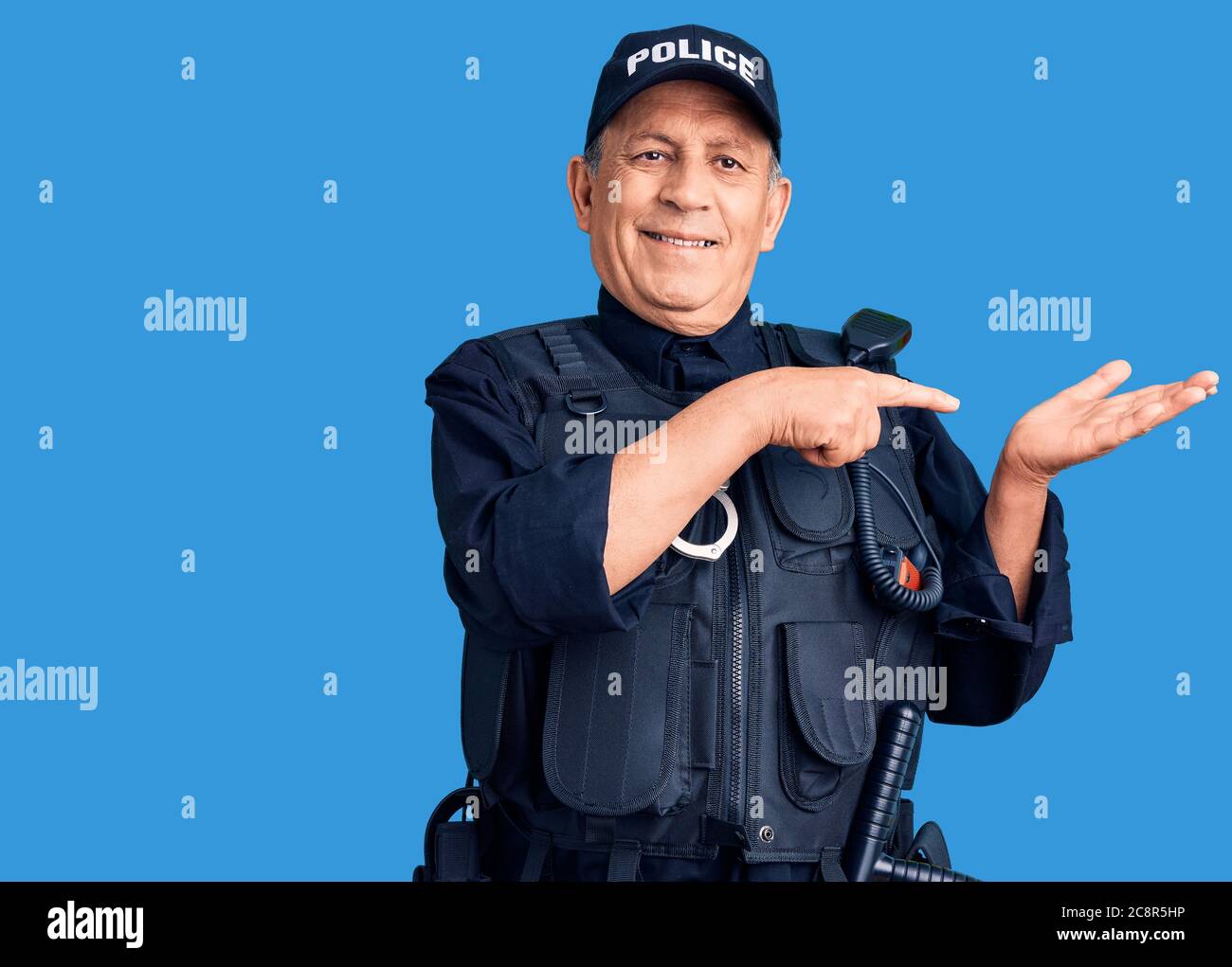 Senior handsome man wearing police uniform amazed and smiling to the ...