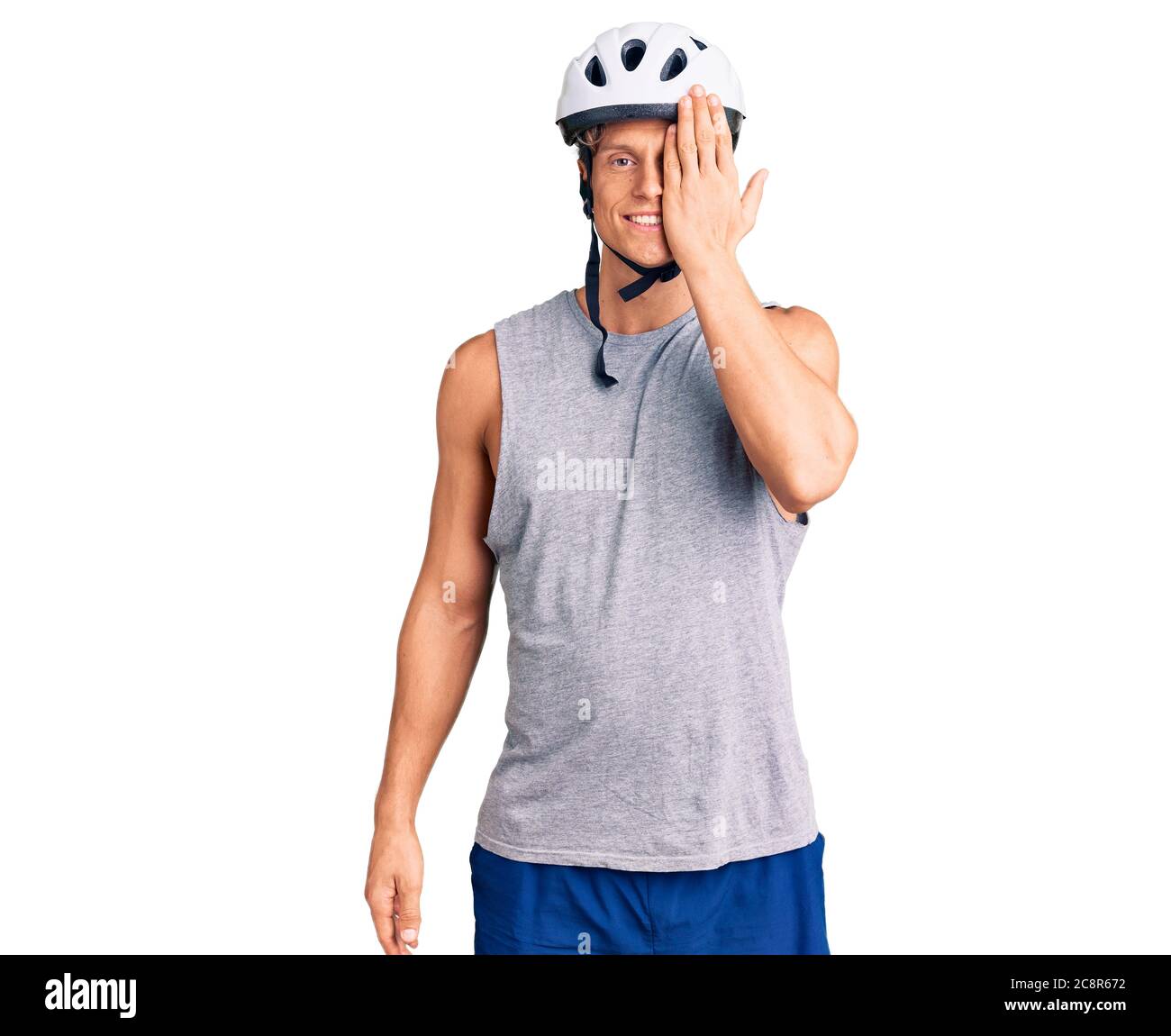 Young handsome man wearing bike helmet covering one eye with hand