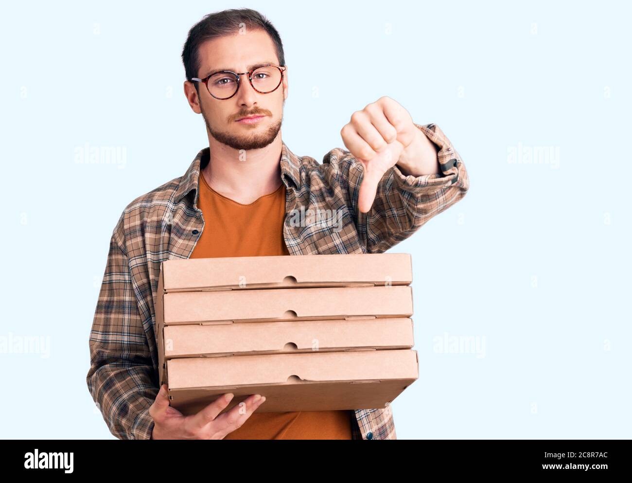 Young handsome caucasian man holding delivery pizza box with angry face ...