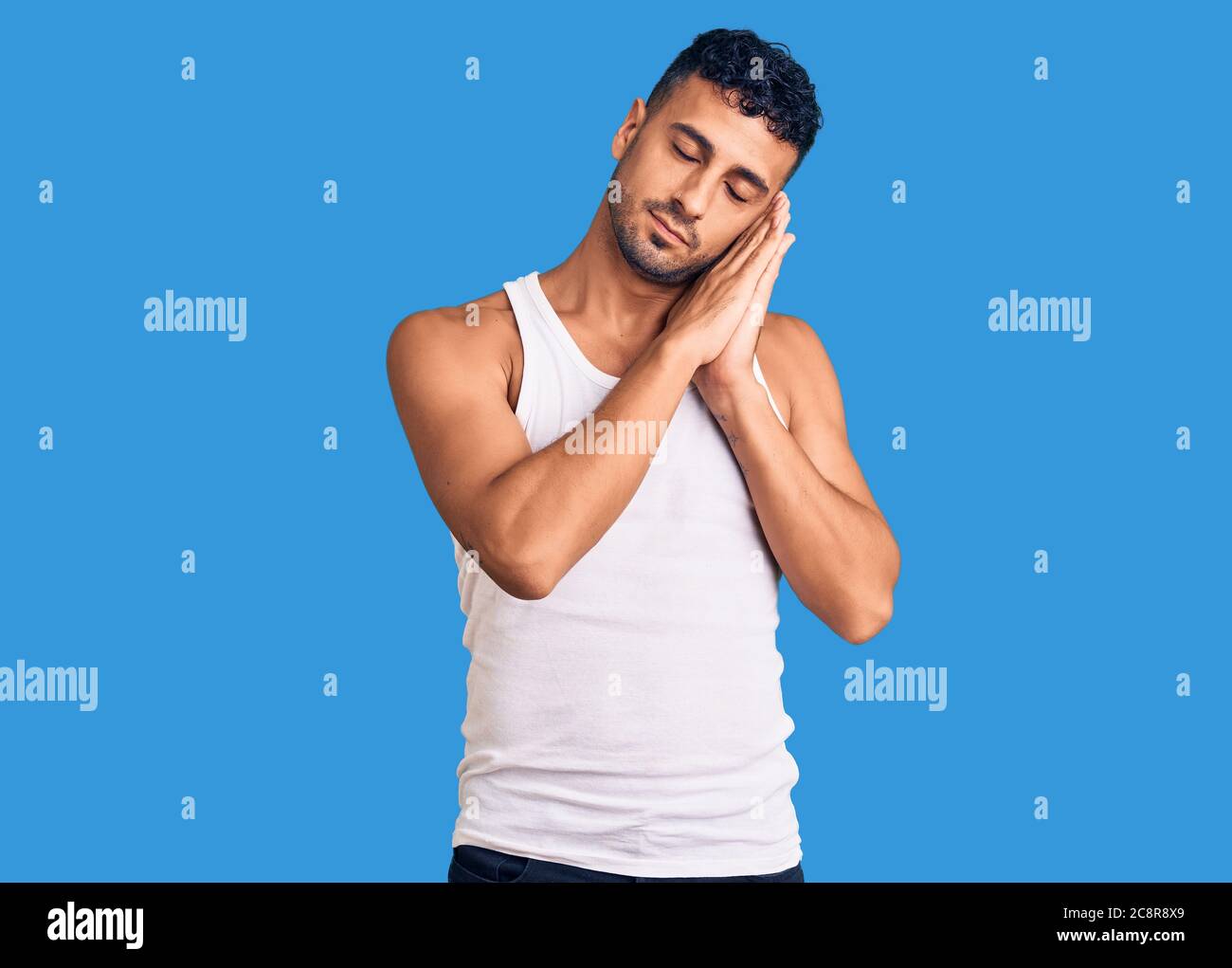 Young hispanic man wearing casual clothes sleeping tired dreaming and ...