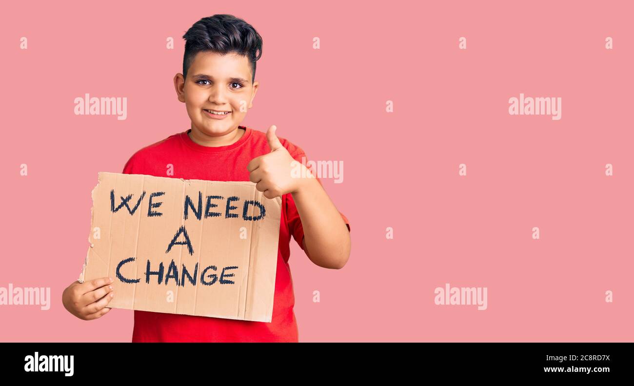 Little boy kid holding we need a change banner smiling happy and ...