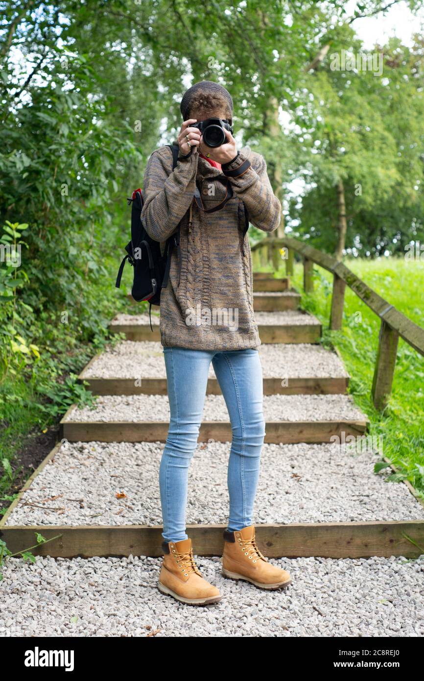 Full length portrait of a young male hobbyist photographer taking a photograph. Natural environment. Theme or concept. UK. Stock Photo