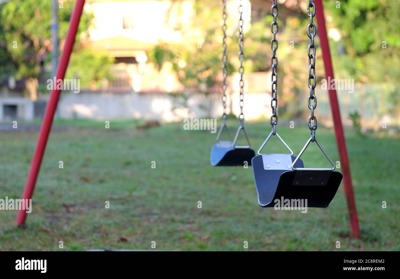 Swing set at a playground that is empty. Warm morning sunlight. Stock Photo