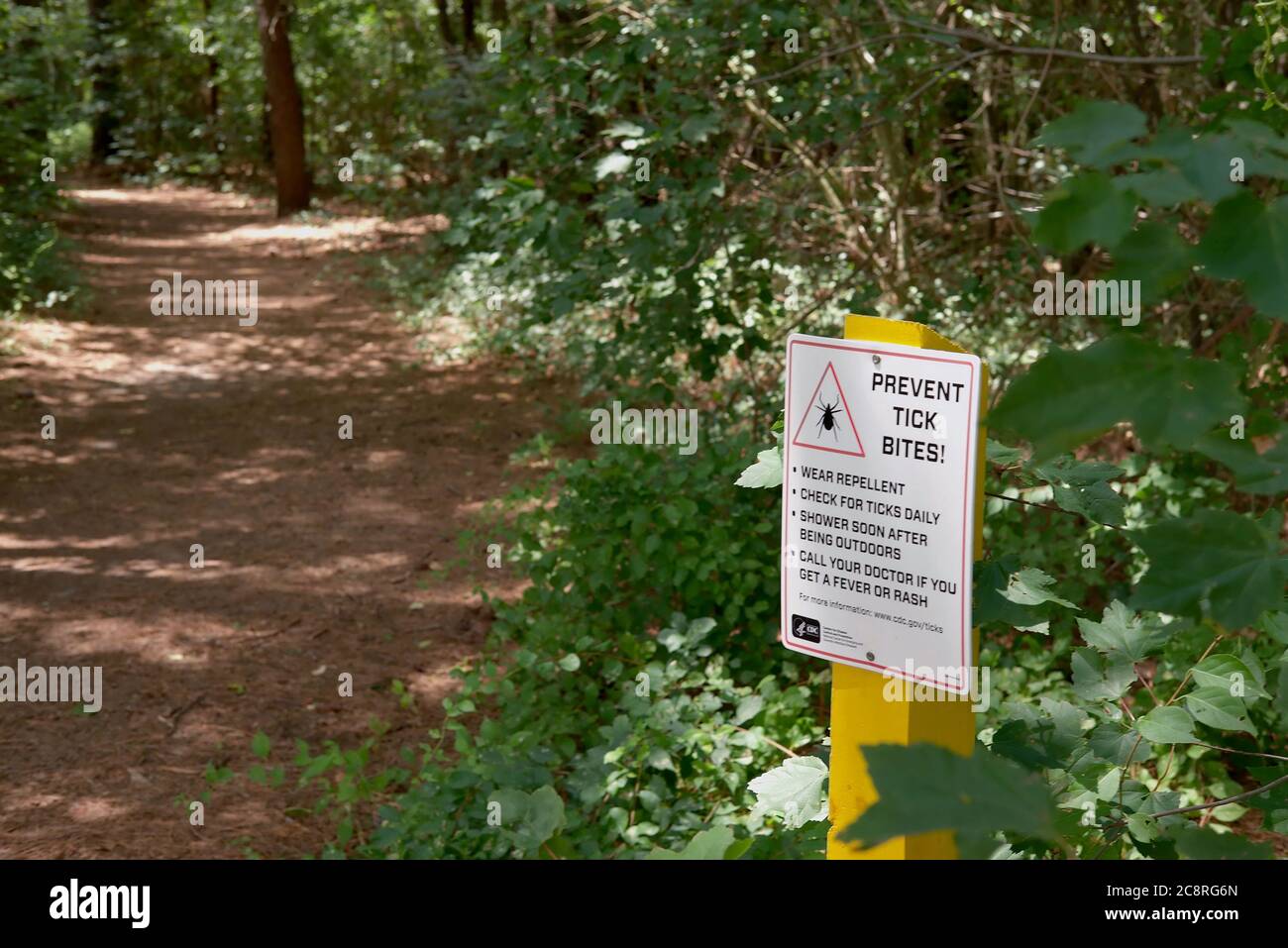 A trail sign cautions hikers about the threat of ticks along the trail at the Chapel Branch Nature Area near Seaford, DE. Stock Photo