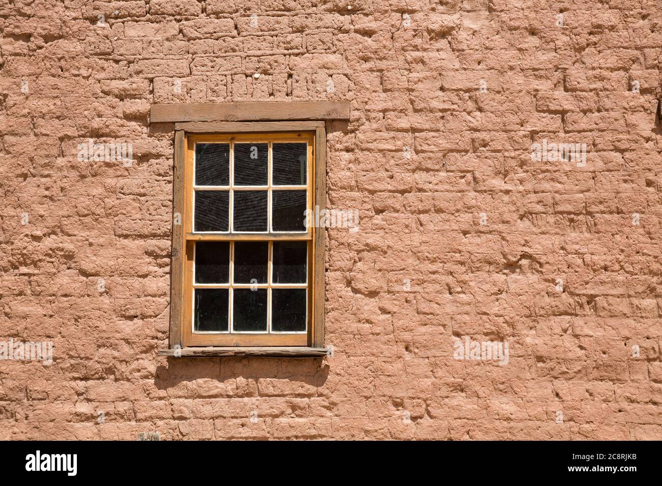 In a small ghost town in the Southern Utah wilderness, a wooden window is set into a red brick building. Stock Photo