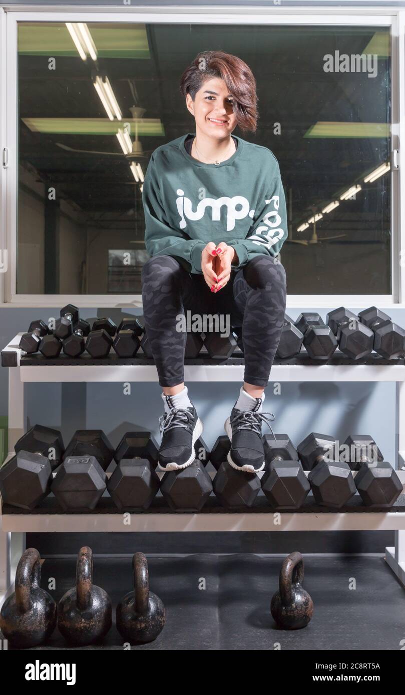 Female Racking Weights Young woman sitting on a rack of barbell weights Stock Photo - Alamy