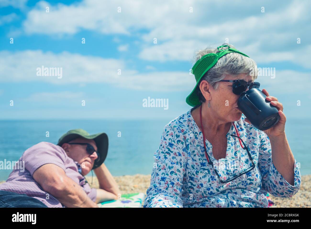 A senior couple on the beach relaxing with a mug of coffee Stock Photo ...