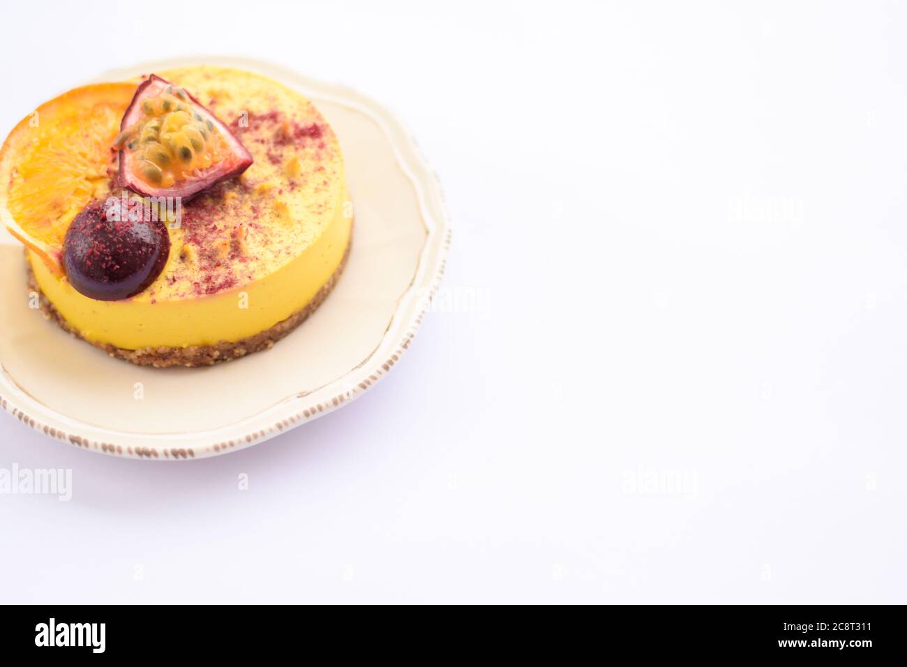 Raw homemade mango puree cake with a piece of fig and orange on top on