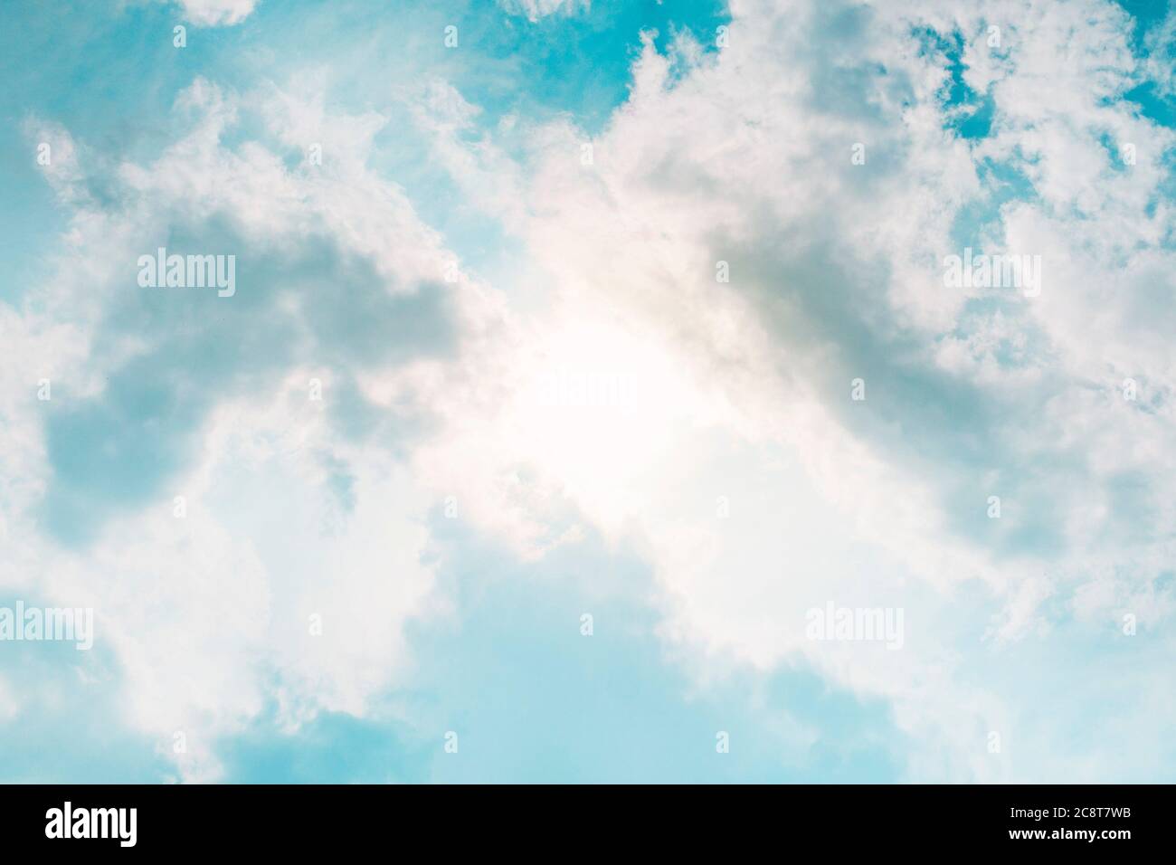 sun behind clouds in blue sky in summer day Stock Photo