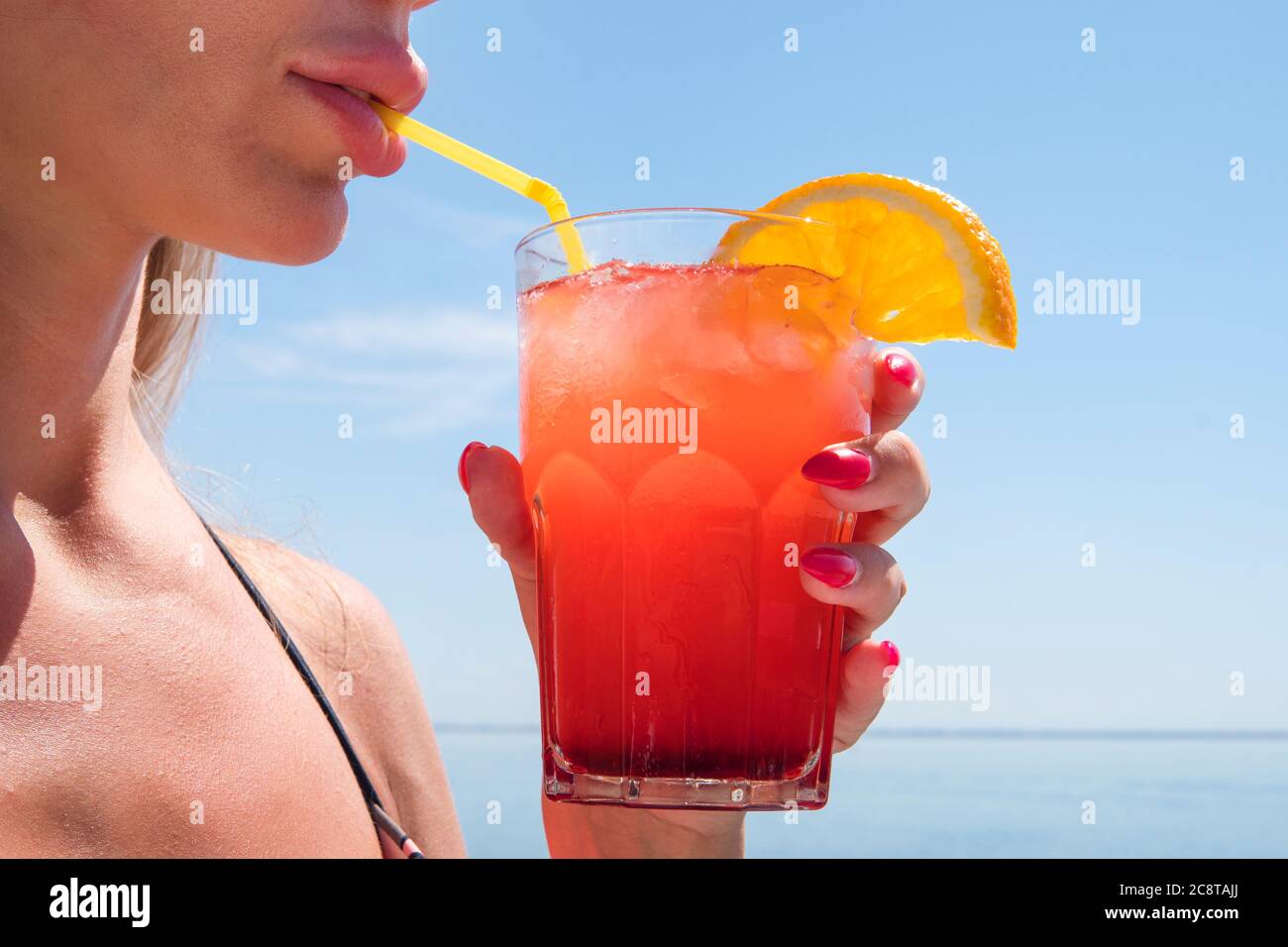 Beauty portrait young woman with glass of summer cocktail orange juice, organic drink, sea, long drink