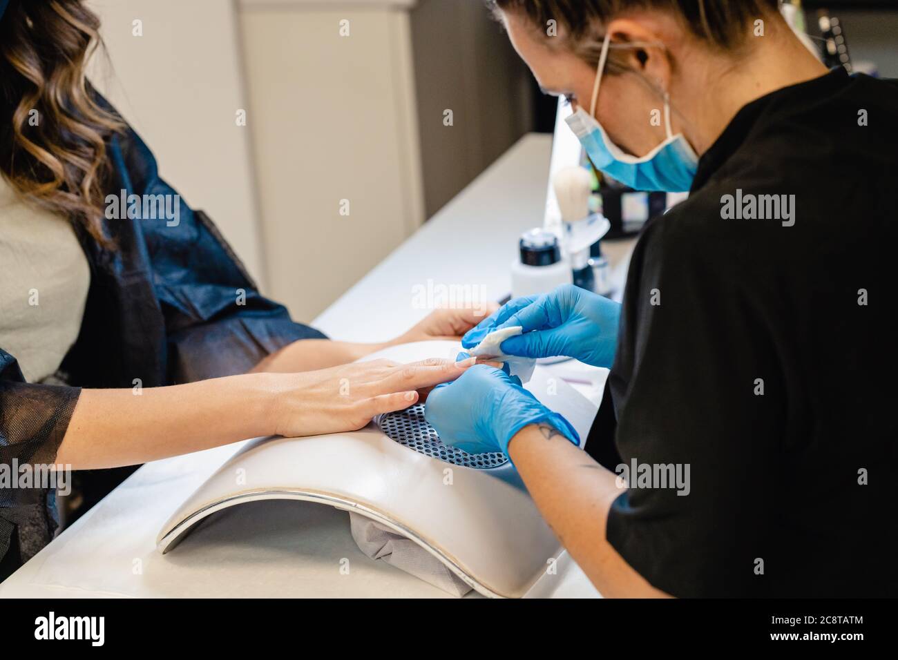 Aesthetician doing the manicure, filing the nails with a file to his client in a beauty center Stock Photo