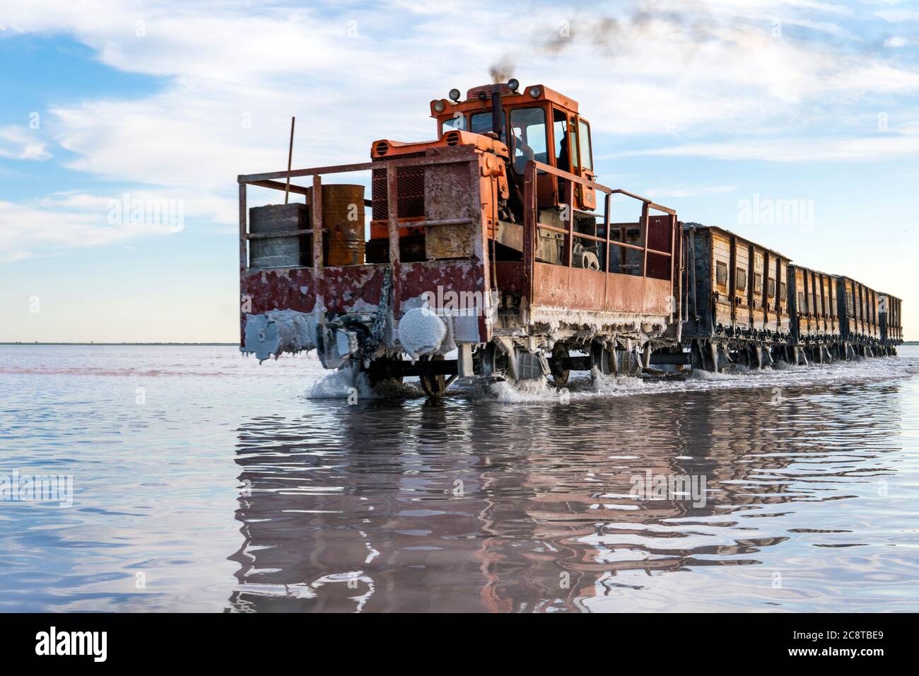 Awesome train rides on rail in the water with white salt on the background of beautiful blue sky. Stock Photo