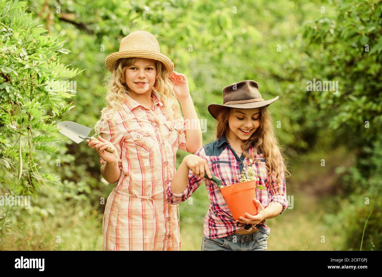 The best job ever. happy farming. spring country side. earth day. summer family farm. protect nature. Rich harvest. children work using gardening tool. small girls farmer in village. Beauty of nature. Stock Photo