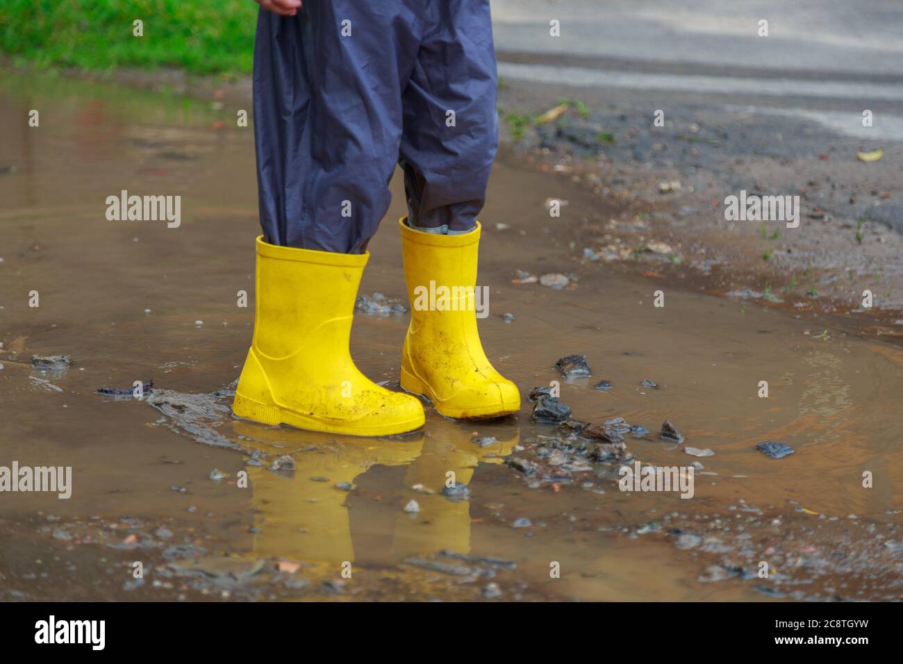 Feet of child in yellow rubber boots jumping over puddle in rain Stock ...