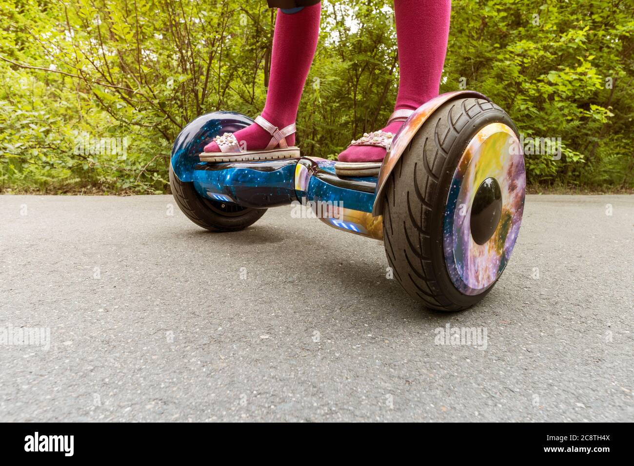 Legs of girl riding on self-balancing mini hoverboard in city Park. Electronic scooter outdoors - personal portable eco transport, gyro scooter Stock Photo