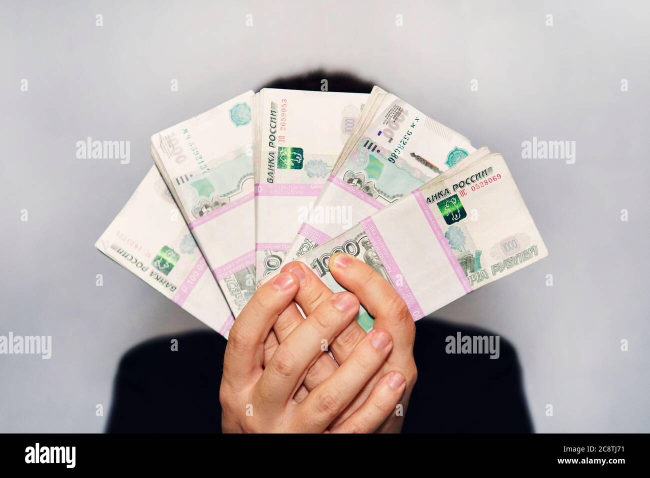 lot of money in the hand of a young businessman on a blue background. A stack of banknotes of Russian rubles with a face value of 1000 rubles Stock Photo