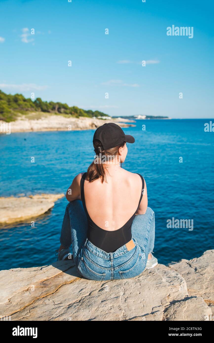 young pretty woman sitting on the cliff looking at sea Stock Photo - Alamy