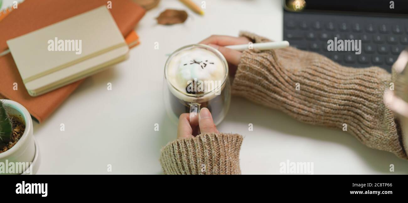 Cropped shot of female designer hands holding a cup of beverage on ...
