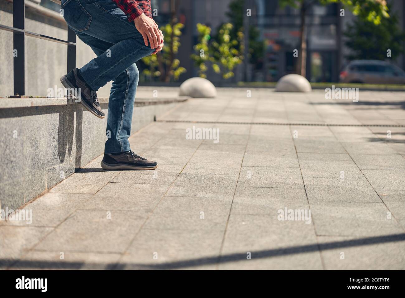 Man in jeans suffering from knee pain outdoors Stock Photo Alamy