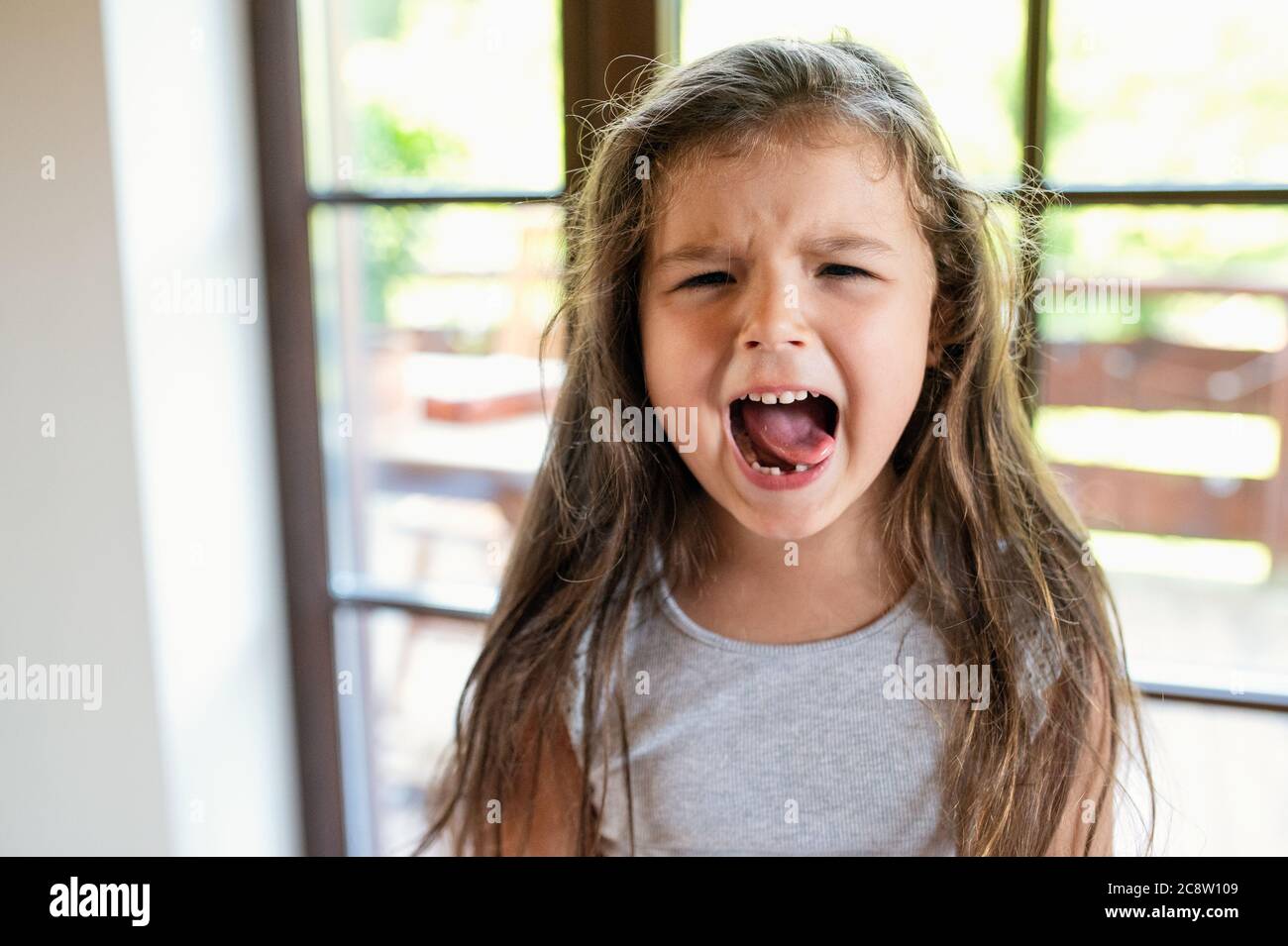 Portrait of angry small girl indoors, crying. Stock Photo