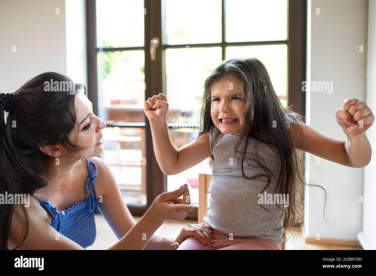 Portrait of mother and angry small girl indoors, tantrum concept. Stock Photo