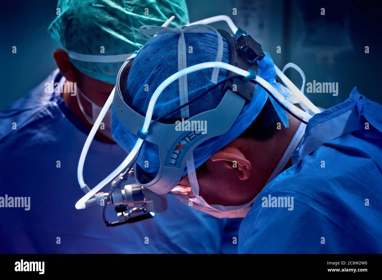 Surgeon performing a thoracic operation using a fibre-optic head-light. Stock Photo